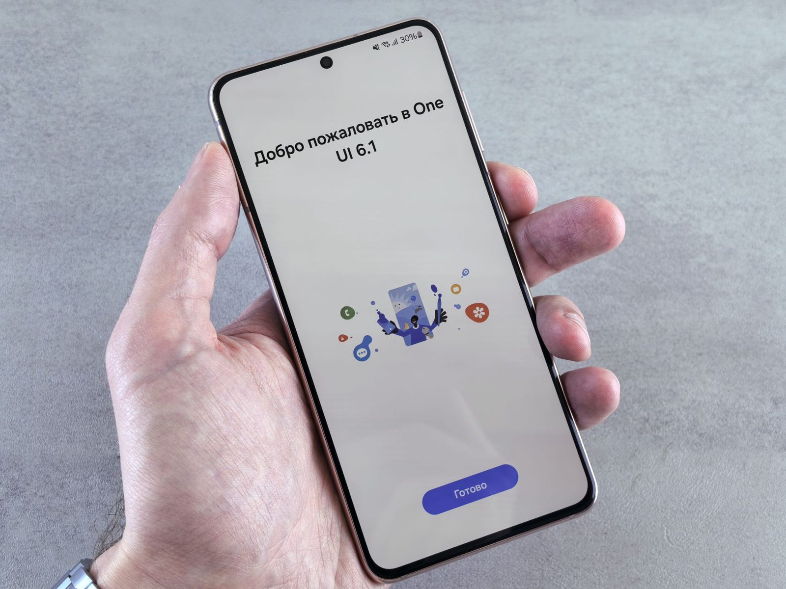 Una mano sostiene un teléfono Android con una pantalla de bienvenida de One UI durante la configuración.