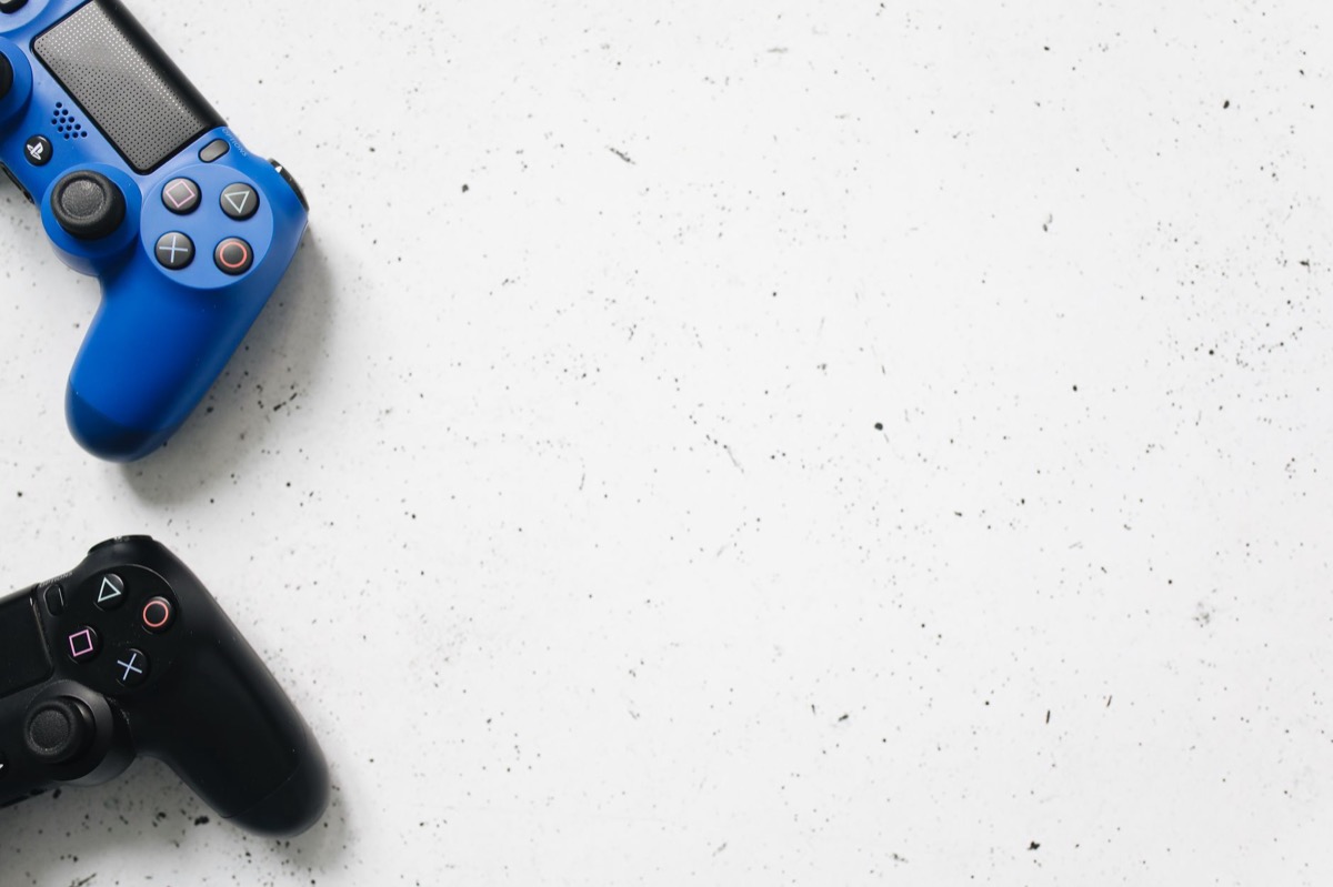 Controladores de juegos azules y negros dispuestos sobre una superficie blanca mínima.