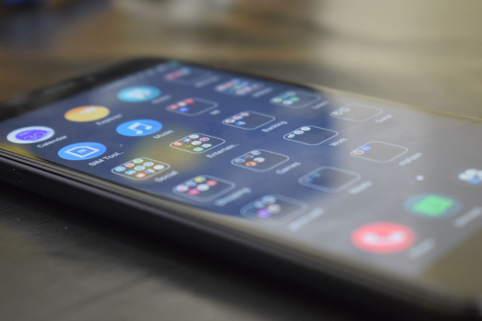 Primer plano de un teléfono inteligente sobre una mesa, con su pantalla de inicio de aplicaciones vista en ángulo.