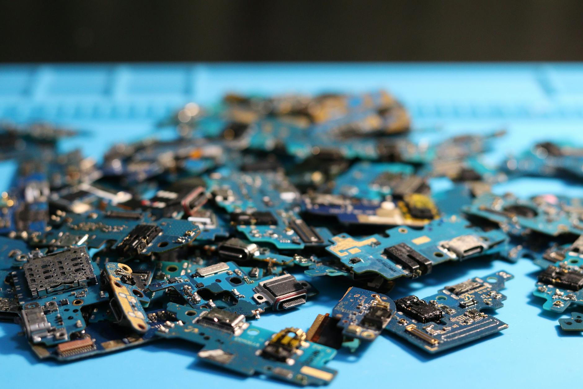 A triptych composition showing enterprise device intake, a technician workbench, and sorted electronic components representing the ITAD, refurbishment and recycling chain.