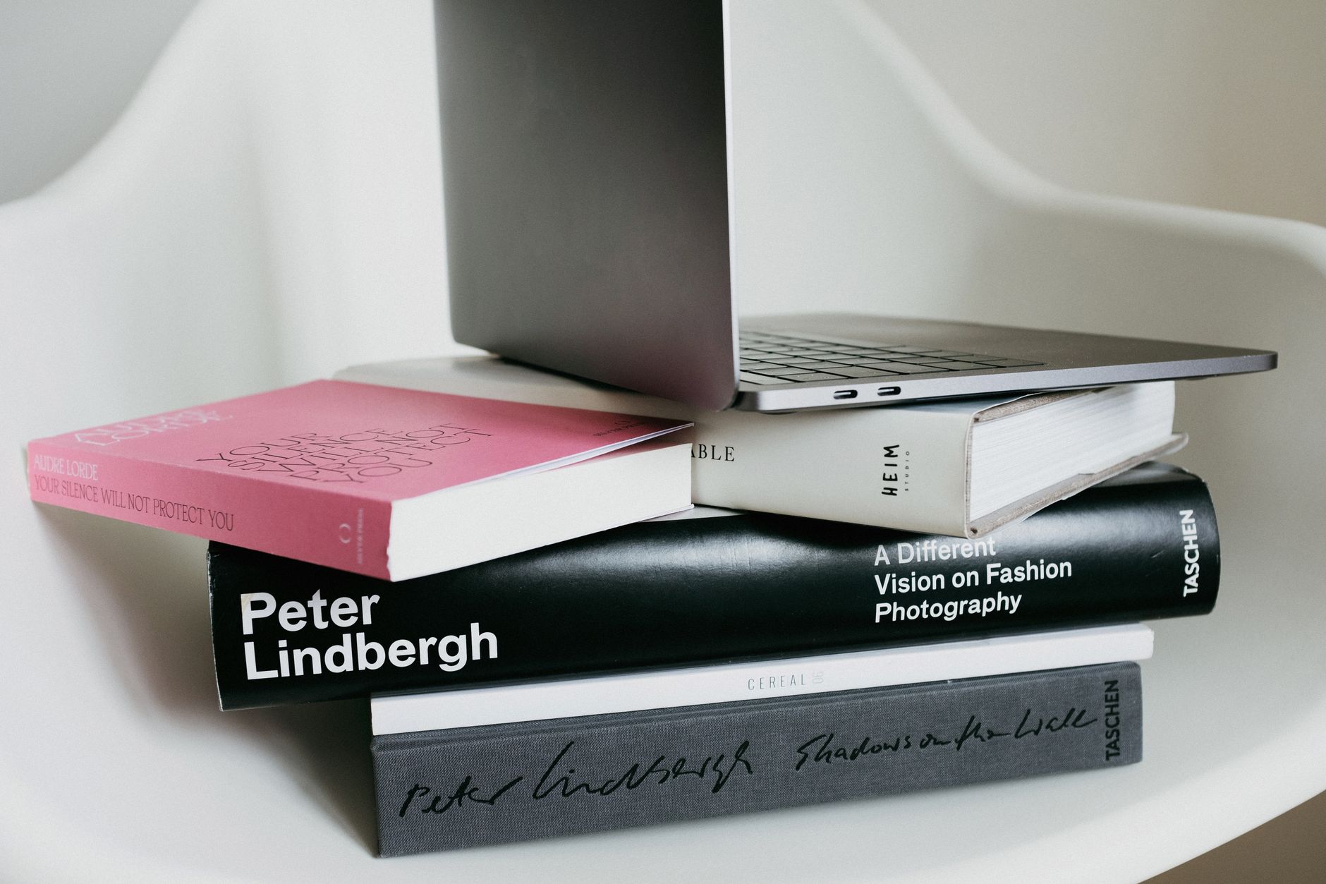 A stack of laptops piled on an office desk.