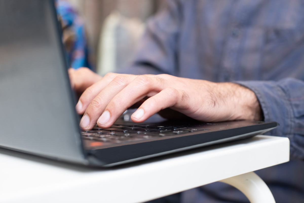Primer plano de manos escribiendo en el teclado de una computadora portátil en un entorno profesional.