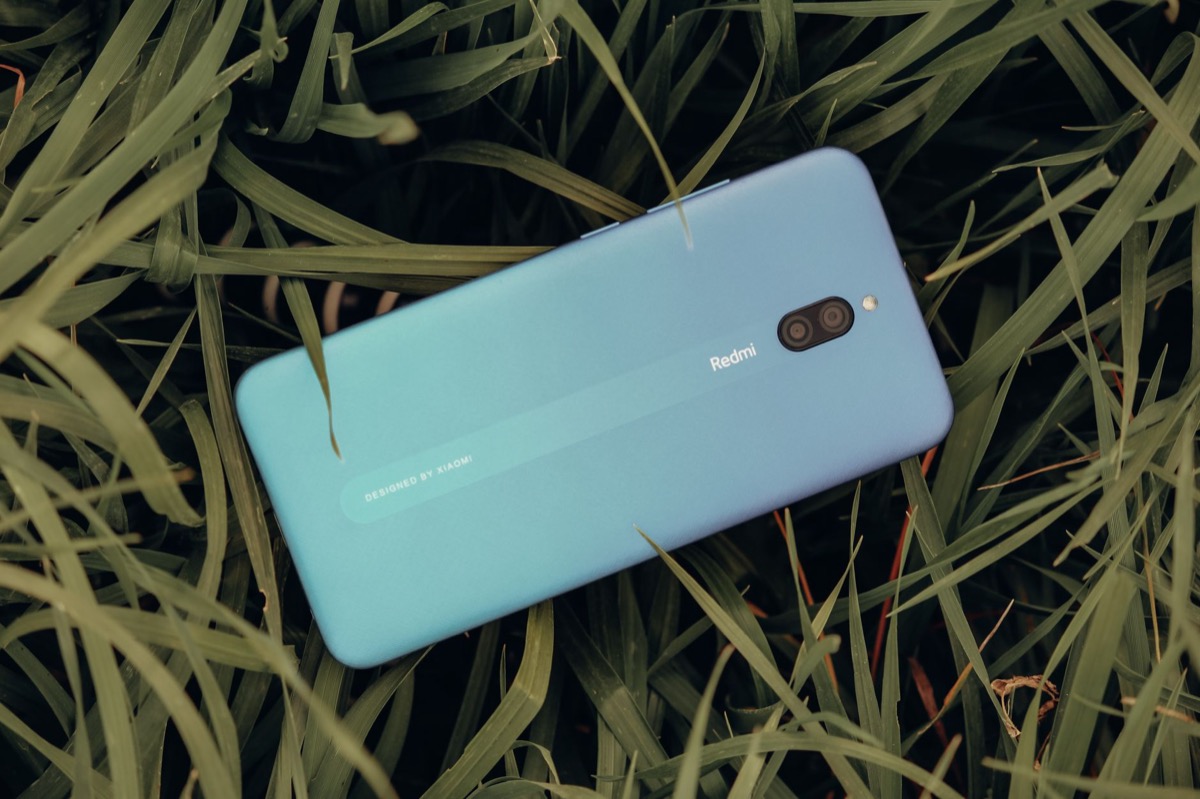 Un teléfono inteligente azul descansando al aire libre sobre una exuberante hierba verde.