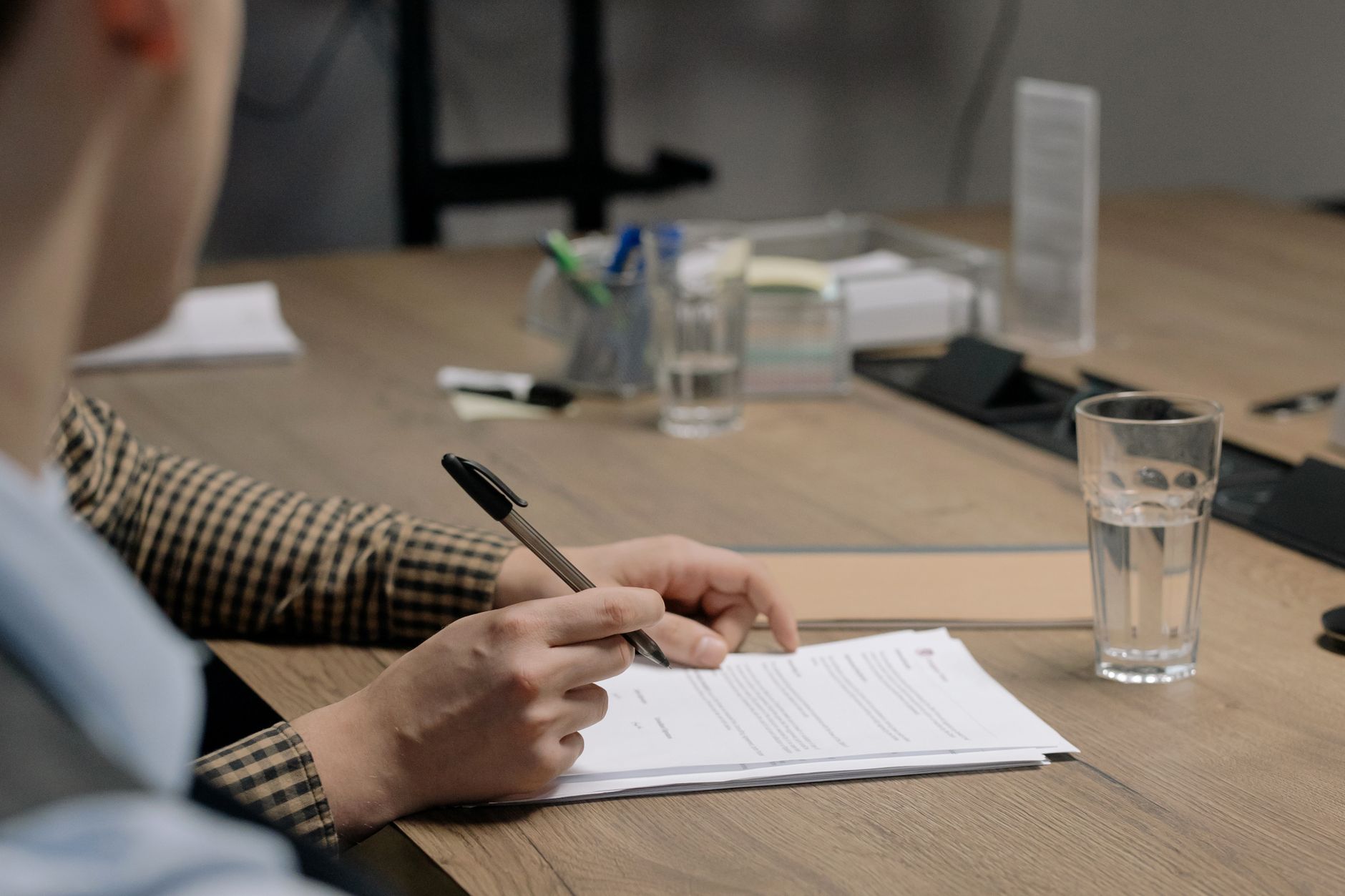 A person signing a business document at a desk during company onboarding.