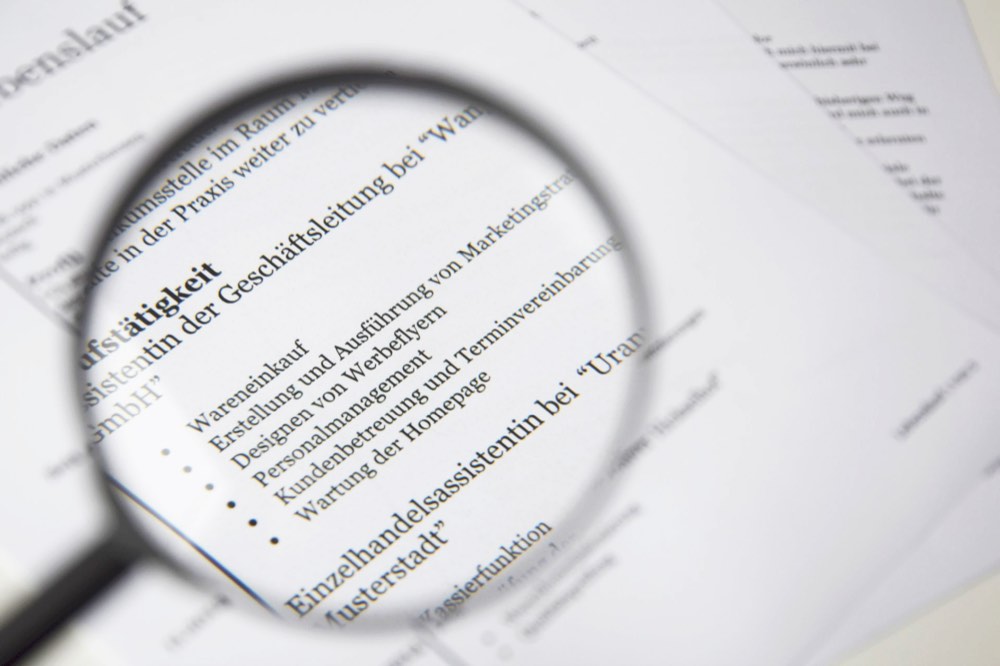 Primer plano de un documento comercial bajo una lupa, que representa una investigación de fraude y estafa.