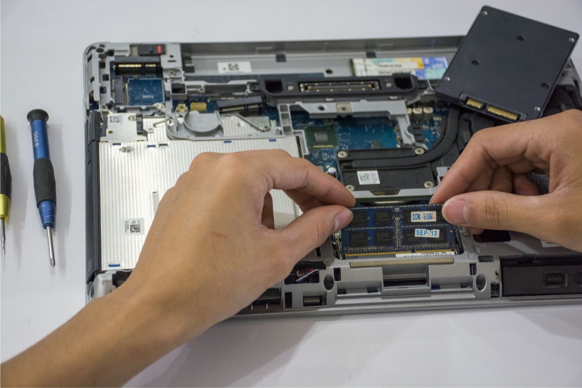 Primer plano de un técnico que ensambla los componentes internos de una computadora portátil utilizando herramientas.