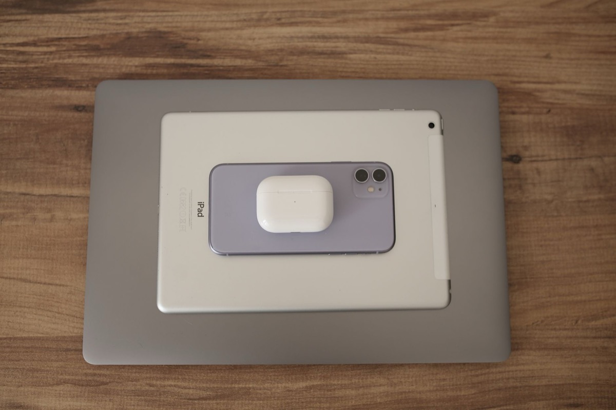Una disposición plana de dispositivos de tecnología moderna, incluidos un teléfono inteligente, una tableta y auriculares sobre una mesa de madera.